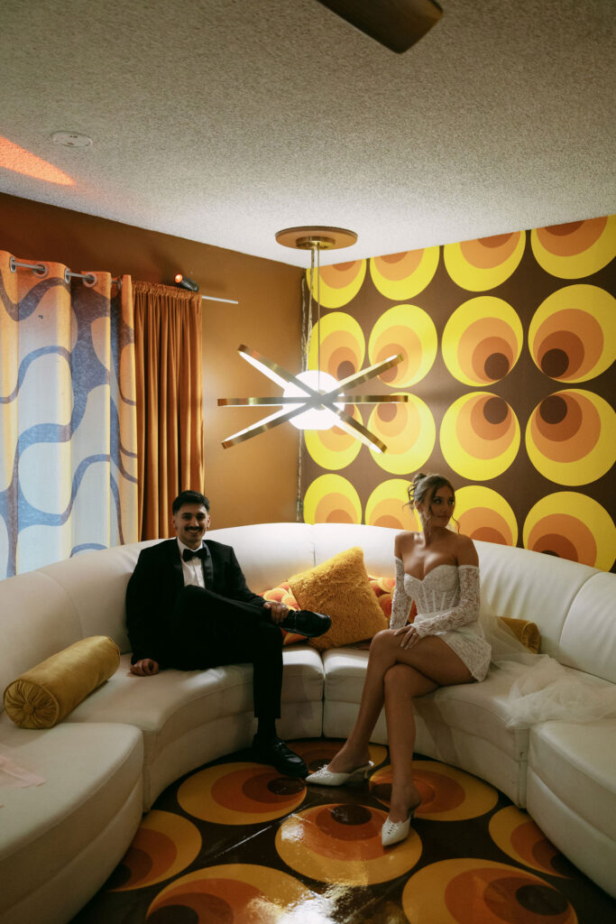 Bride and groom sitting on a white vintage retro couch for their Las Vegas elopement