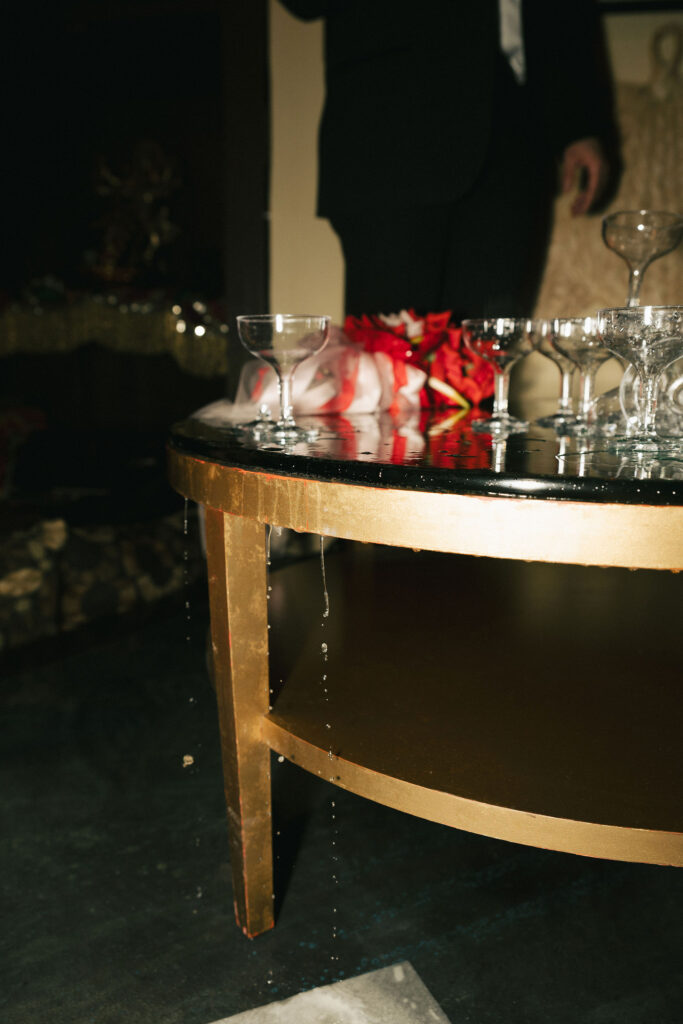 Close-up of champagne tower glasses spilling over a gold table at a lively retro Las Vegas elopement celebration.