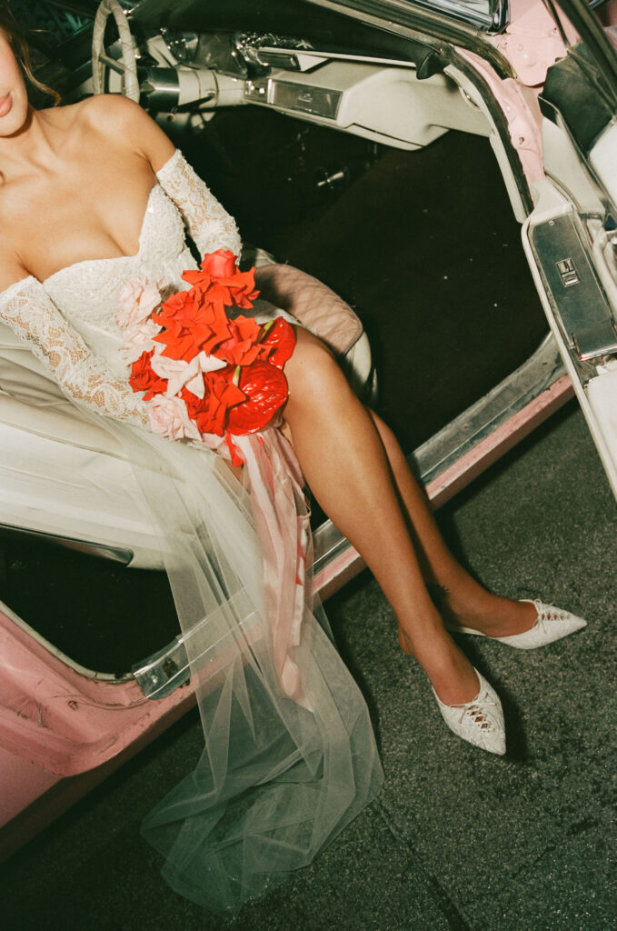 Close up shot of a bride sitting in the pink Cadillac and holding her bouquet