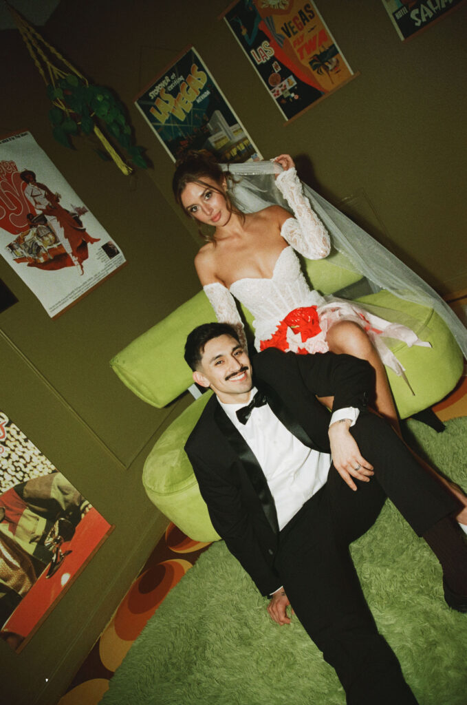 Bride sitting on a green retro chair while the groom sits on the floor in front of her during their retro film elopement.