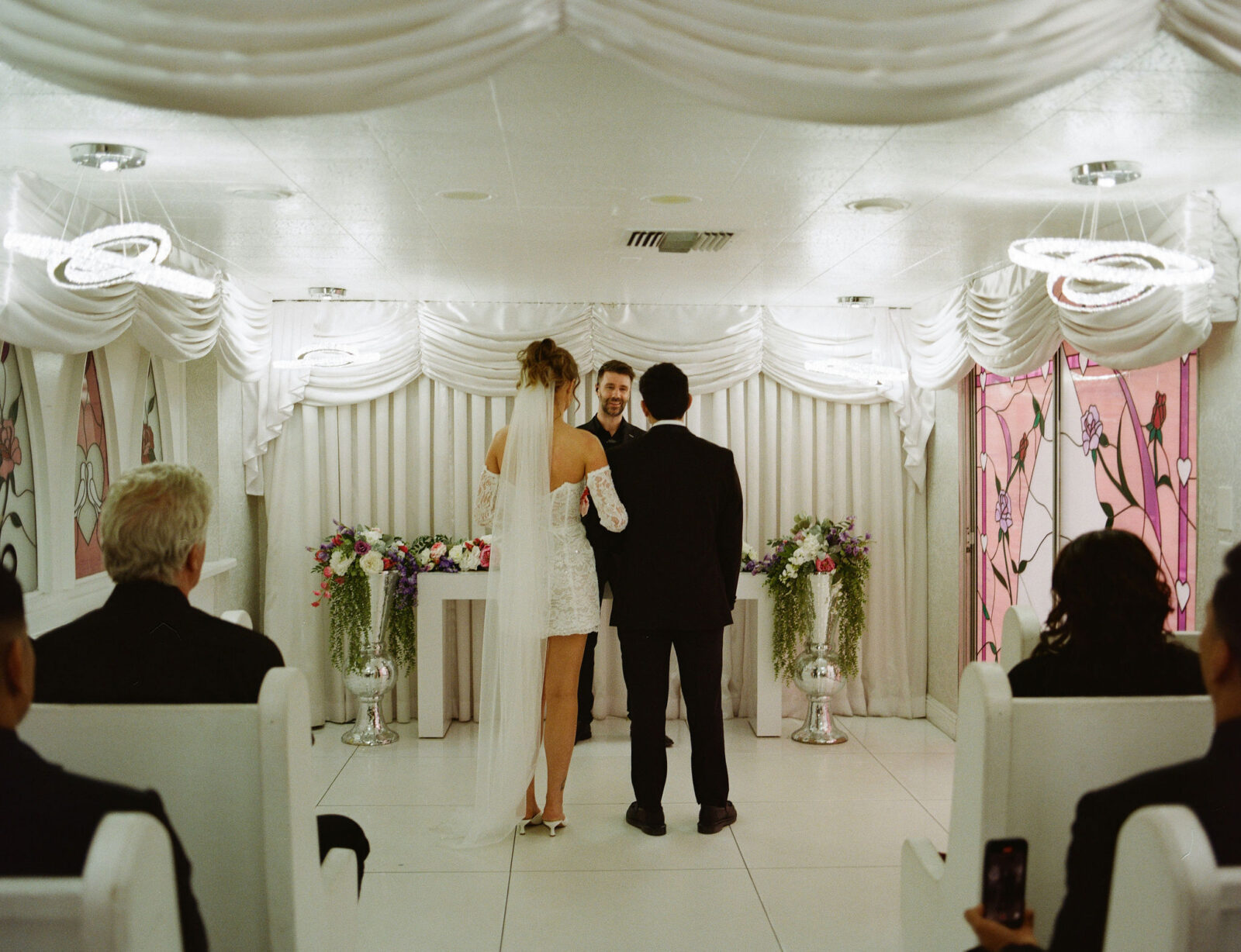 Bride and groom standing at the altar during their Little White Wedding Chapel ceremony on film