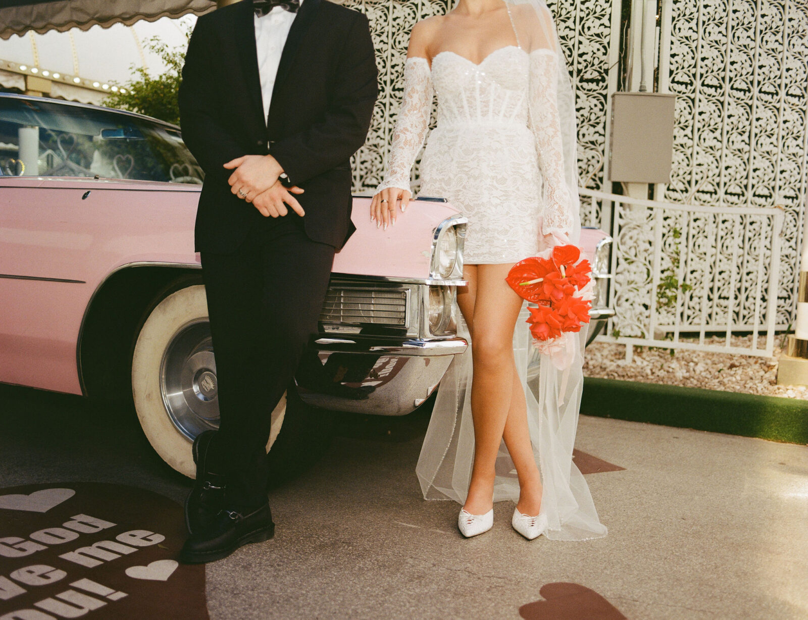 Bride and groom posing with the Pink Cadillac at The Little White Wedding Chapel