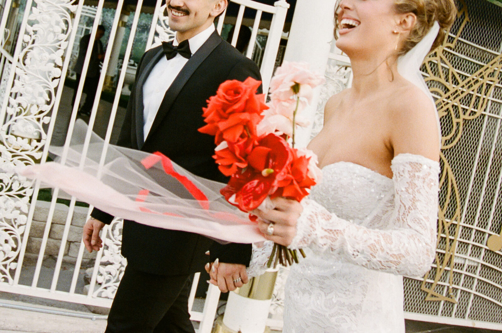 Candid film shot of a bride and groom laughing outside of The Little White Wedding Chapel in Las Vegas