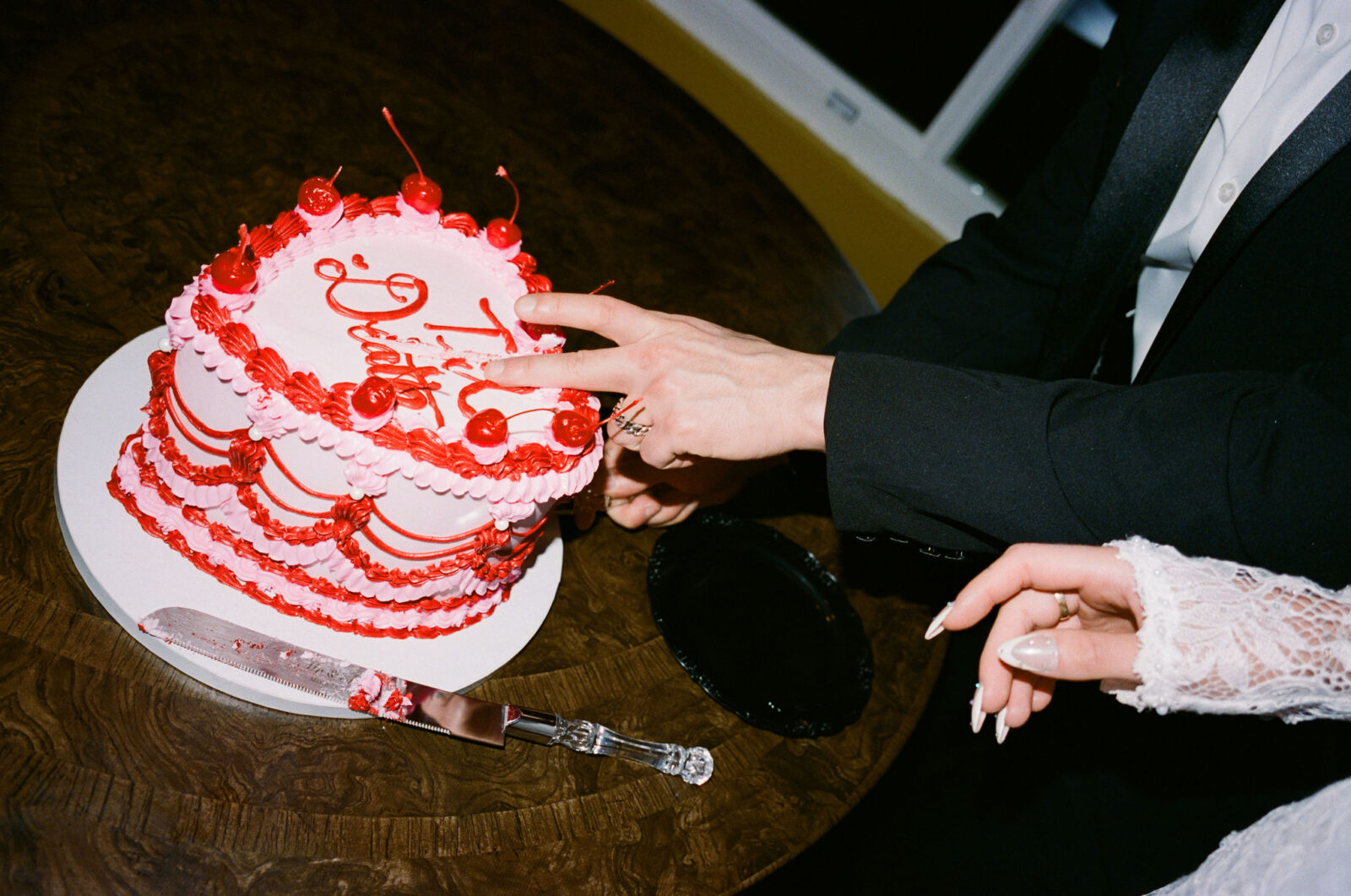 Bride and groom cutting into a retro pink and red wedding cake during their film elopement celebration.
