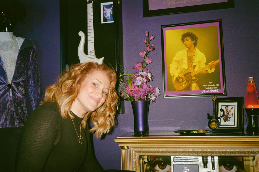 Guest smiling in front of a Prince shrine room inside the retro Vegas home during the elopement reception.