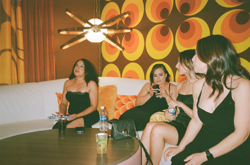 Guests in black attire mingling inside a 70s-inspired Vegas mini-mansion during a retro film elopement.