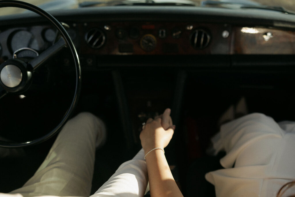 Couple holding hands in a classic Rolls Royce for their desert engagement session