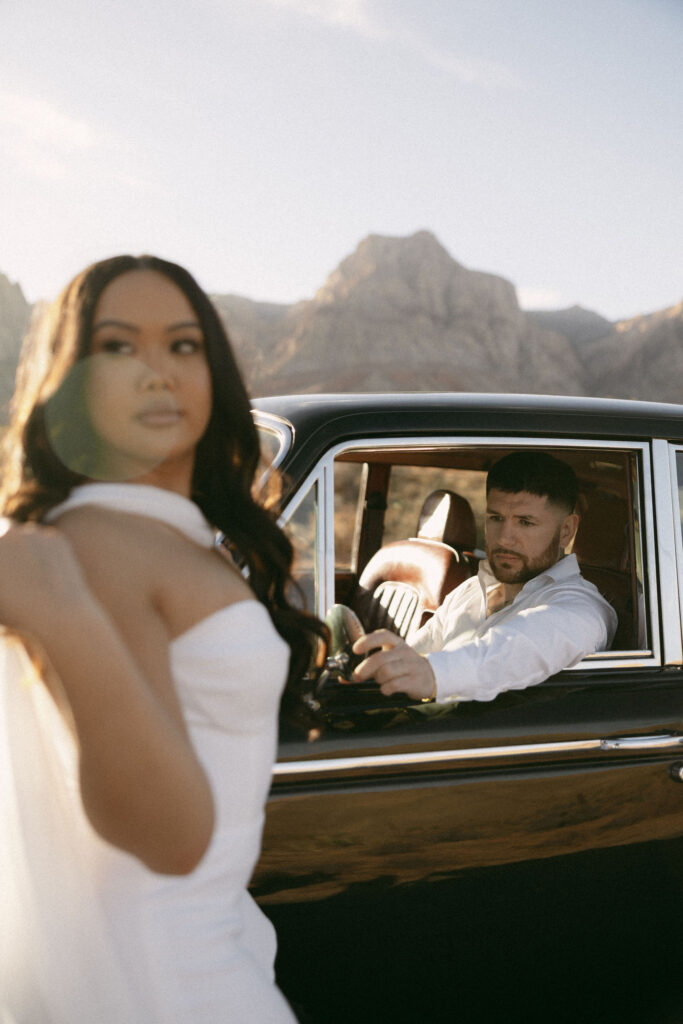 Man sitting in the driver’s seat looking at his partner standing beside the car at Red Rock Canyon.