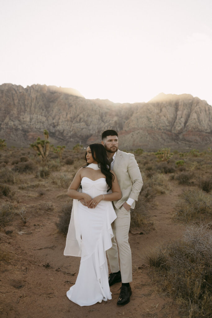 Couple standing together in front of Red Rock Canyon mountains during their desert engagement photos in Las Vegas.