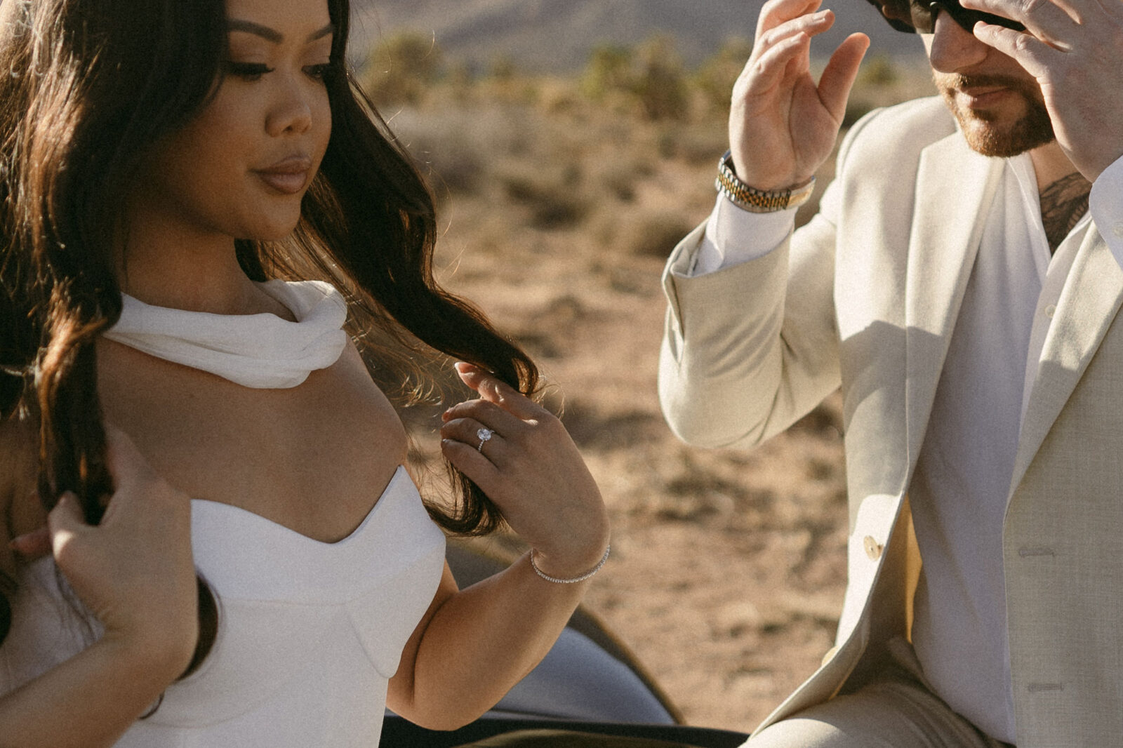 Close-up of a woman adjusting her hair and engagement ring during desert engagement photos at Red Rock Canyon.