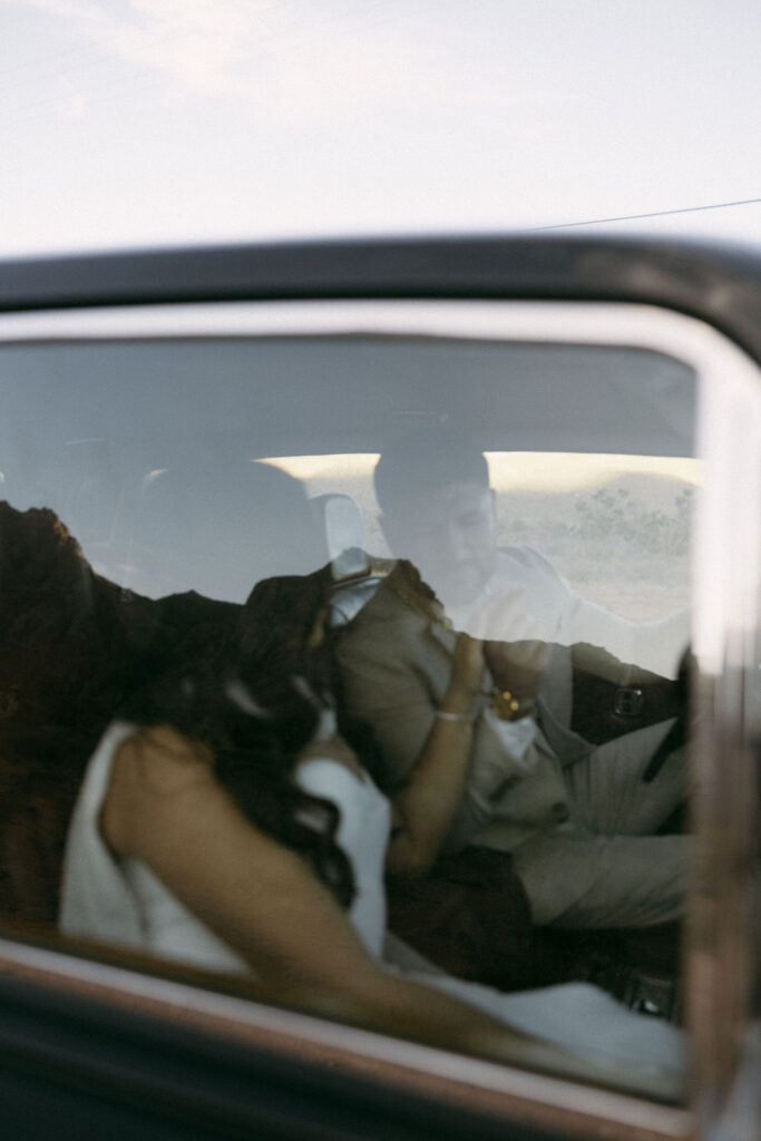 Romantic reflection shot of the couple sitting inside a vintage car during their desert engagement photos in Las Vegas.