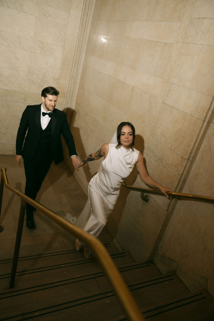 Newlyweds walking up the stairs together inside Grand Central Station following their New York City Hall elopement.