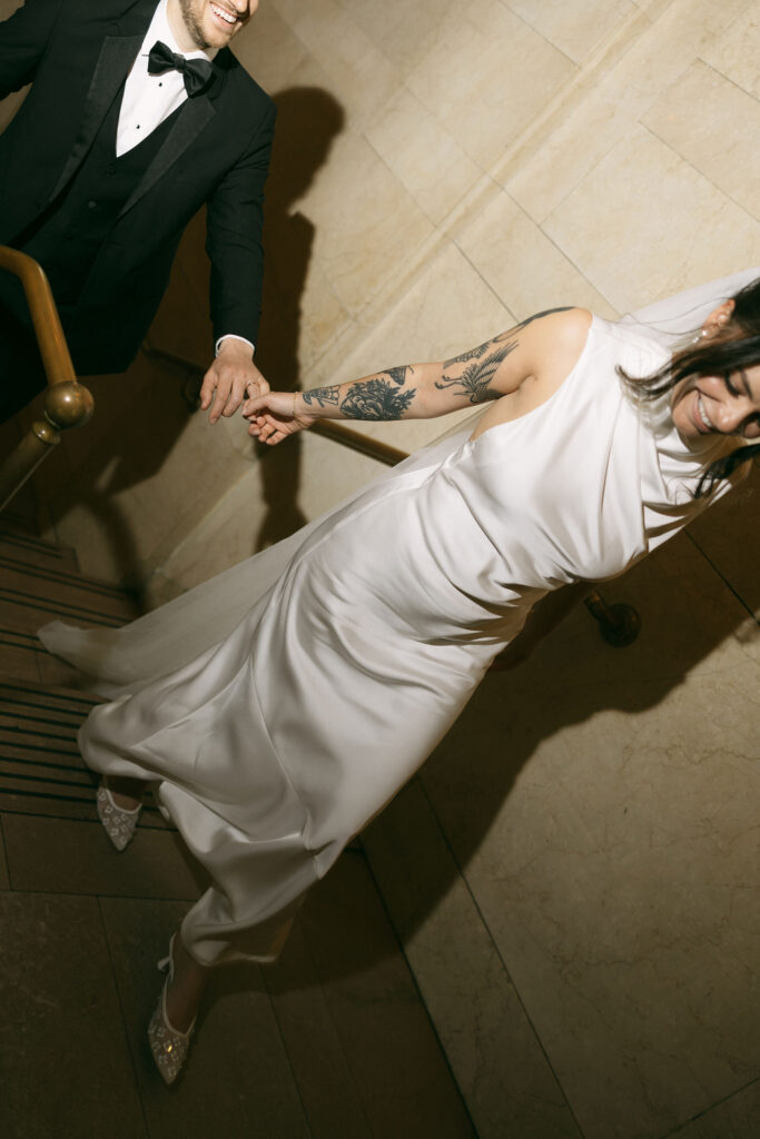 Bride leading her partner up the staircase inside Grand Central Station during post-ceremony portraits.