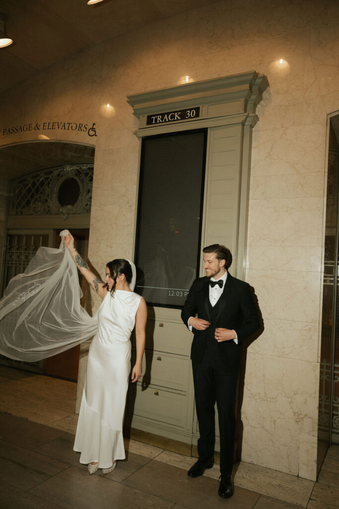 Bride lifting her veil near Track 30 inside Grand Central Station during editorial-style elopement portraits.