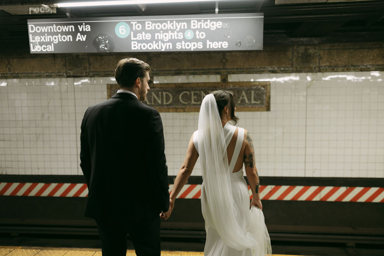 Couple holding hands on a New York City subway platform after their New York City Hall elopement.