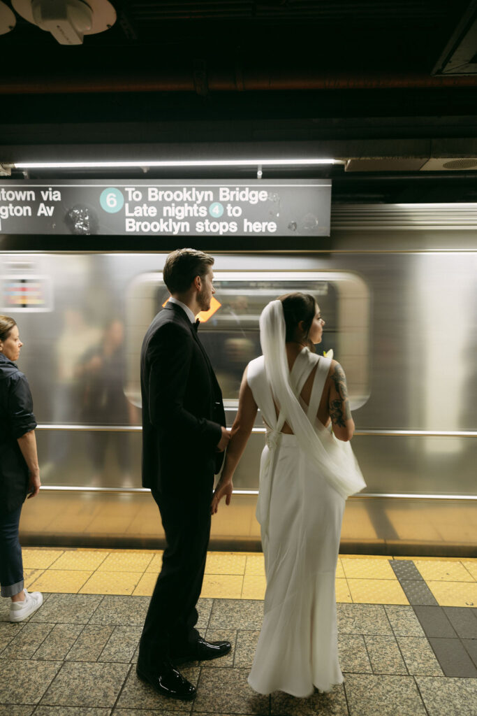 New York City Hall elopement couple standing on the subway platform as a train passes behind them.