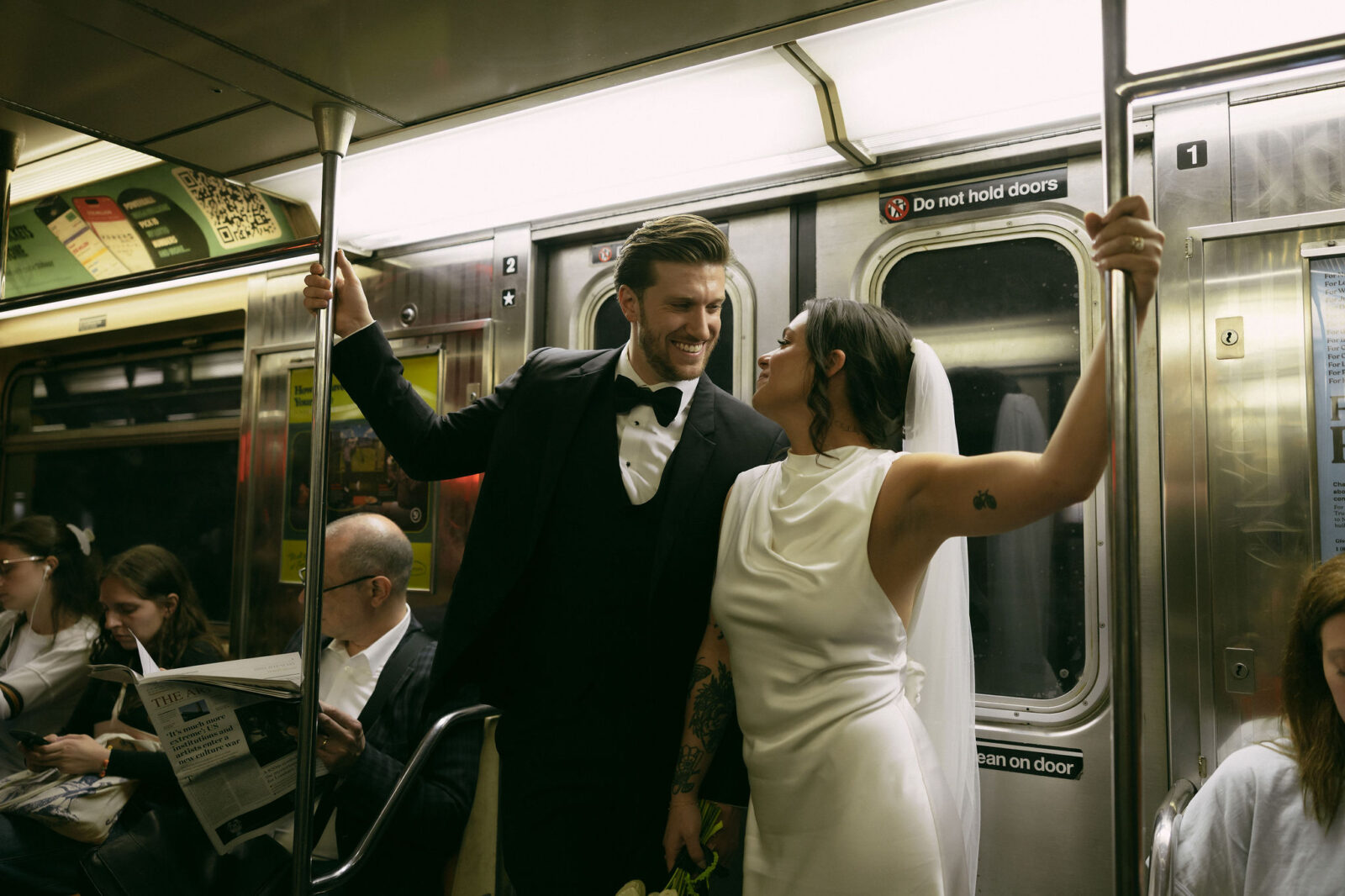 Bride and groom standing together inside a New York City subway car after their City Hall elopement