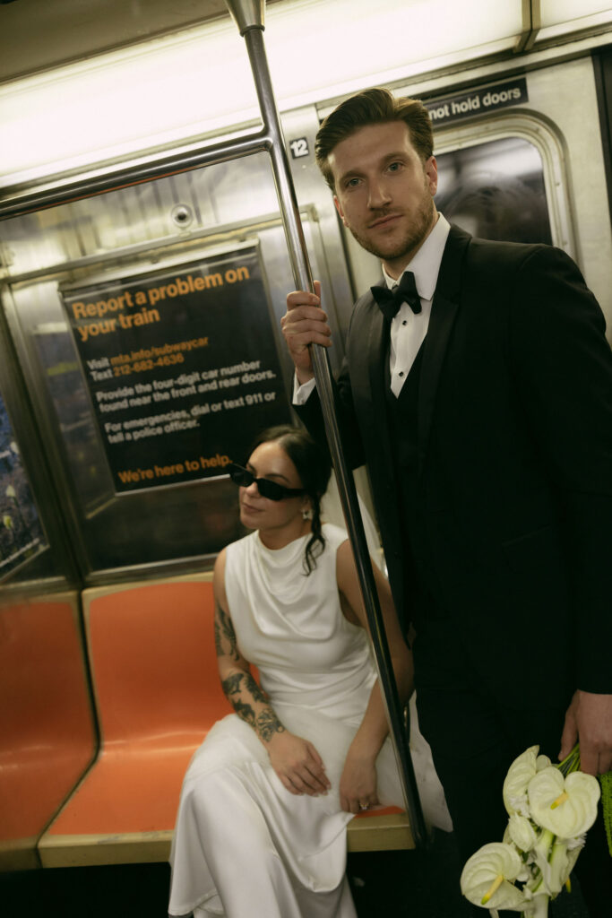 Groom standing in the subway car holding a pole during a New York City Hall elopement portrait session.