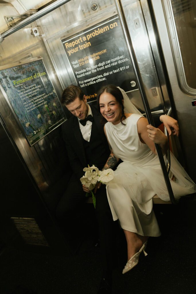 New York City Hall elopement couple laughing together inside a subway car with bouquet in hand.