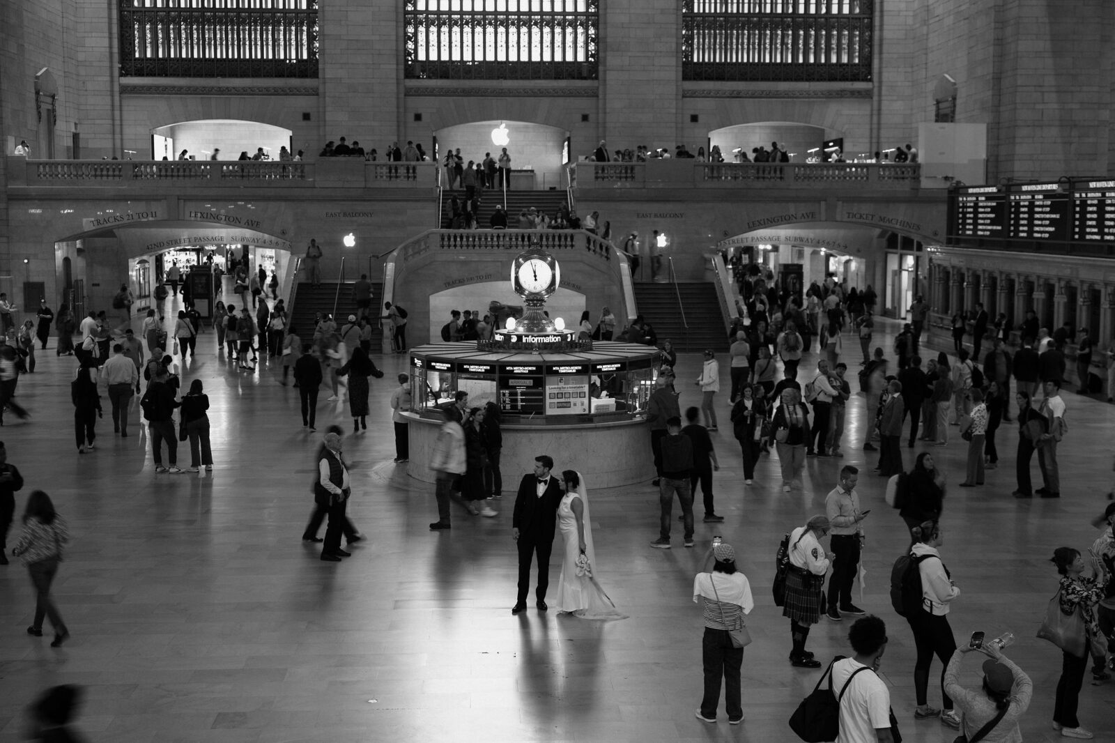 Couple kissing beneath the iconic clock during portraits at Grand Central Station in New York City.