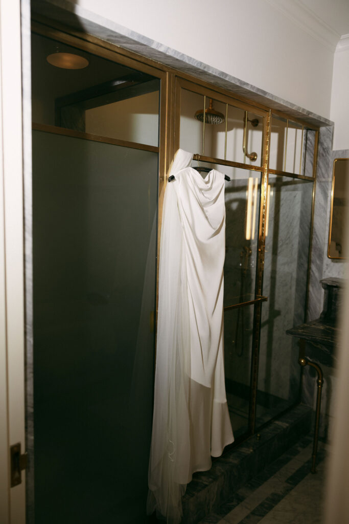 Brides modern New York City elopement dress hanging in the bathroom of The Hotel Chelsea.