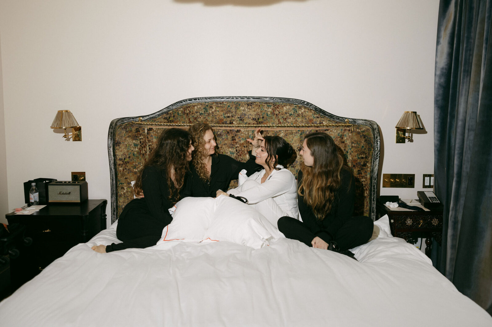 Bride and bridesmaids posing on a bed at The Hotel Chelsea in NYC. 