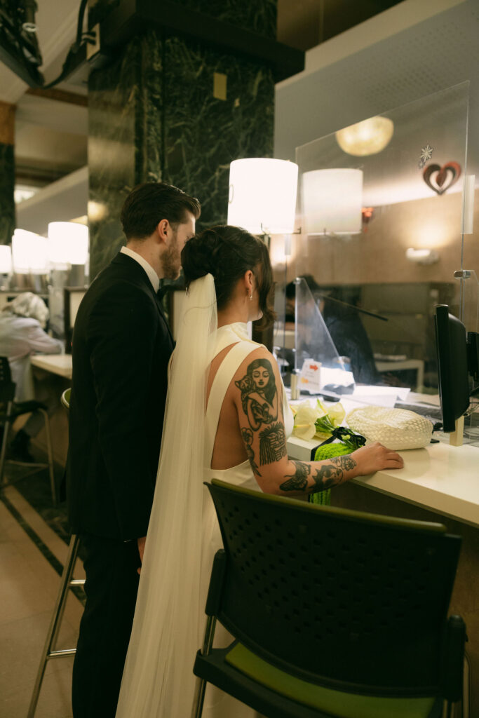 Couple standing at the New York City Clerk’s Office counter during their New York City Hall elopement, completing paperwork before their ceremony.