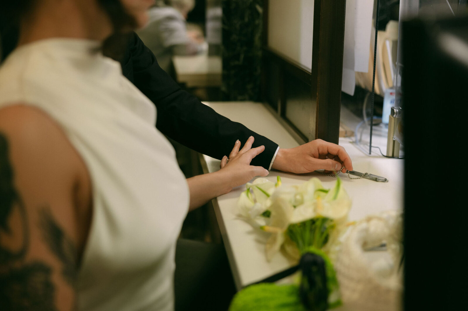 Close-up of bride and groom holding hands at the City Clerk’s Office during a New York City Hall elopement.