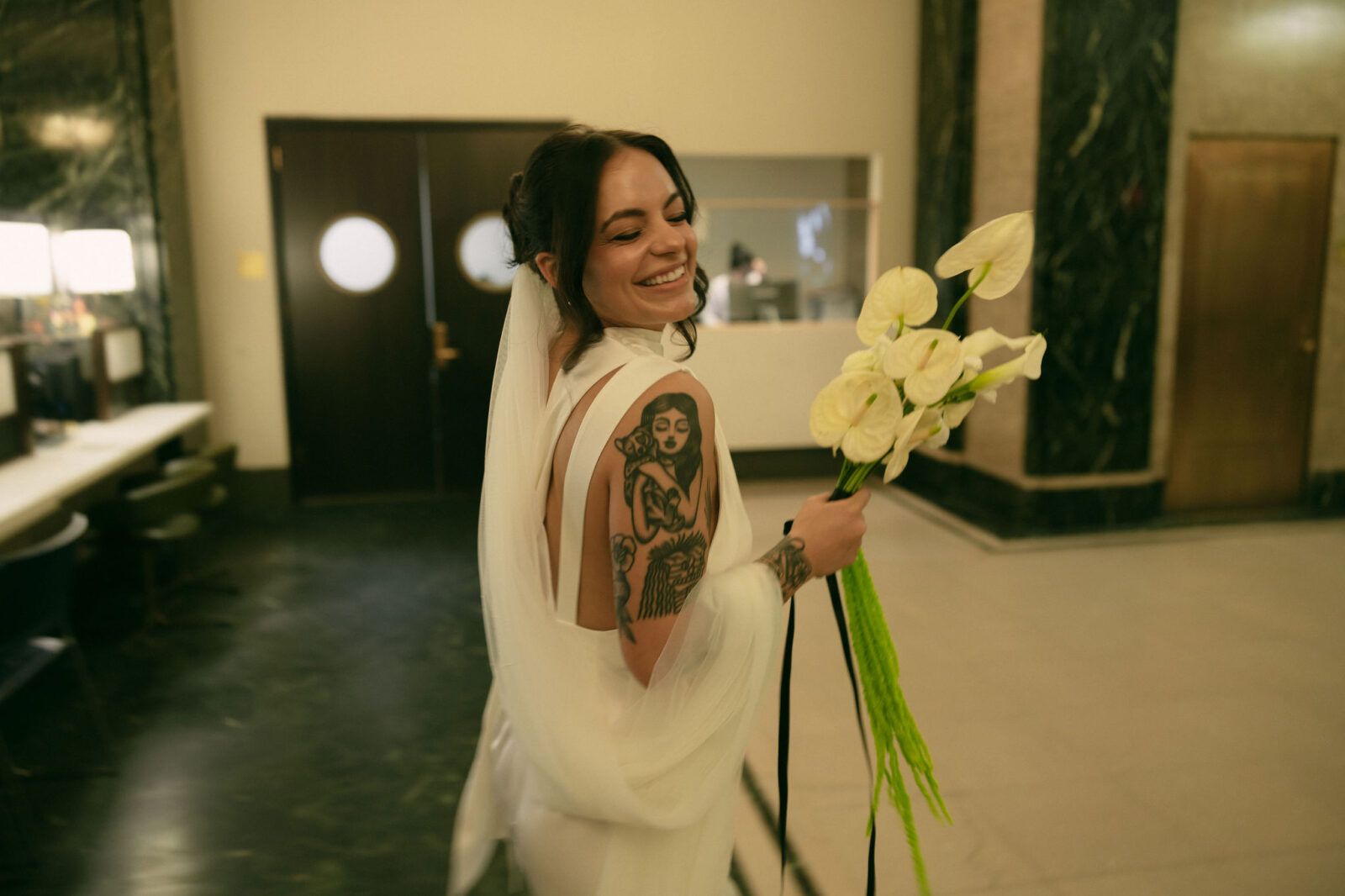 Bride smiling while holding a modern lily bouquet during her New York City Hall elopement.