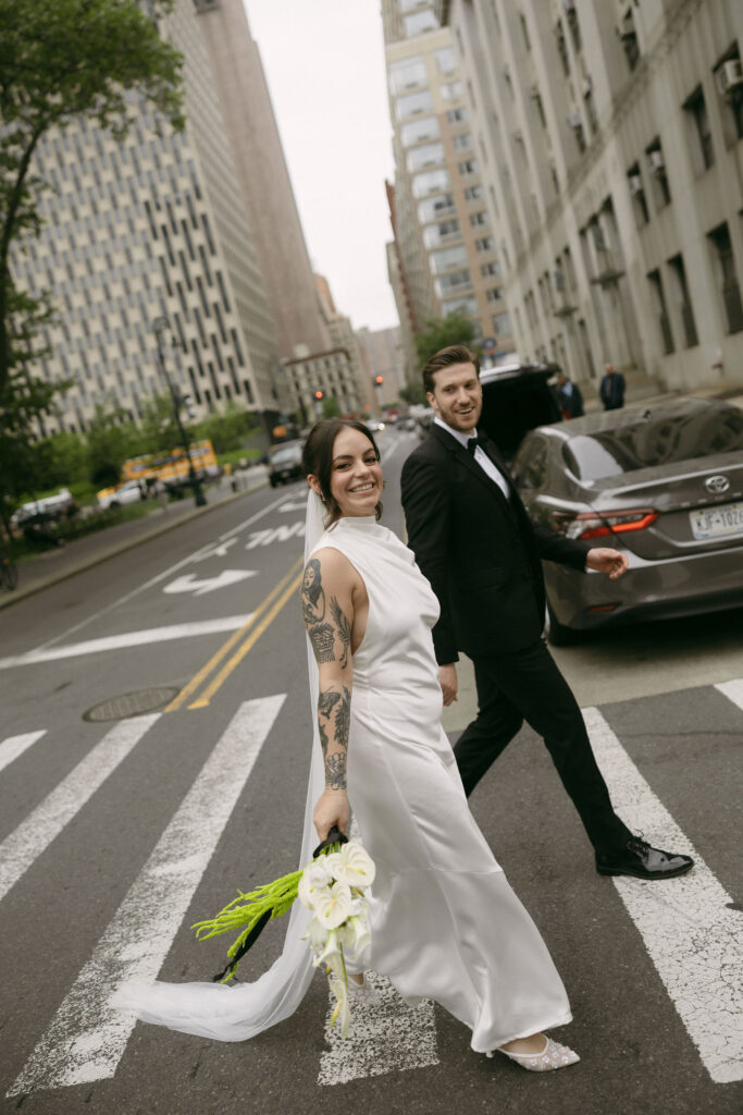 Bride and groom walking hand in hand through downtown Manhattan after their New York City Hall elopement.