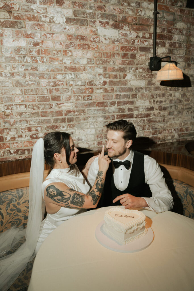 Bride and groom sharing a quiet moment with their wedding cake at Sartiano’s following their New York City Hall elopement.