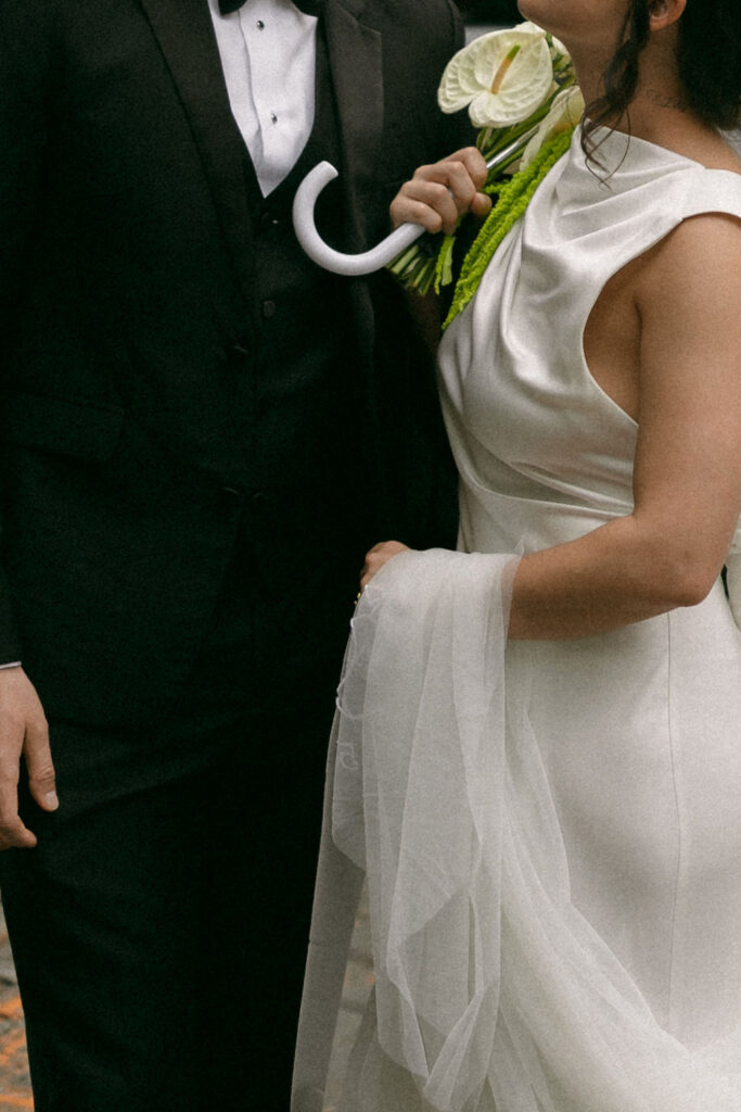 Close-up of a bride and groom’s wedding attire with a modern bouquet.