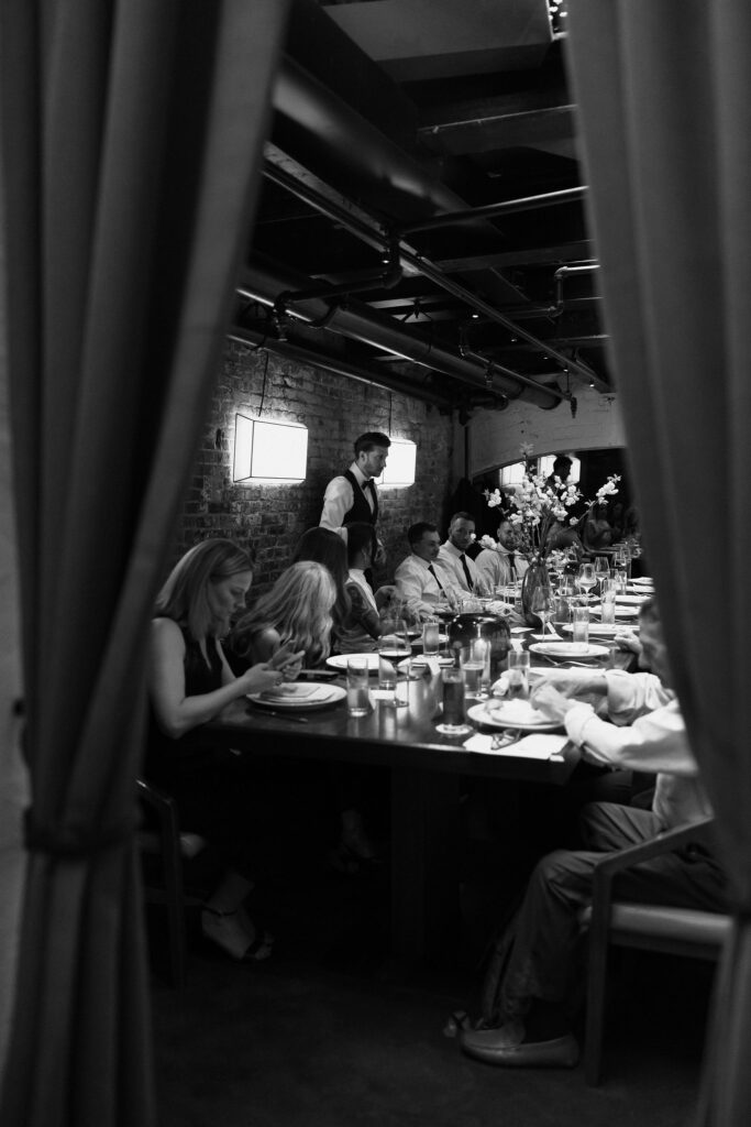 Black and white photo of friends and family sharing a meal at Sartiano’s after a New York City Hall elopement.
